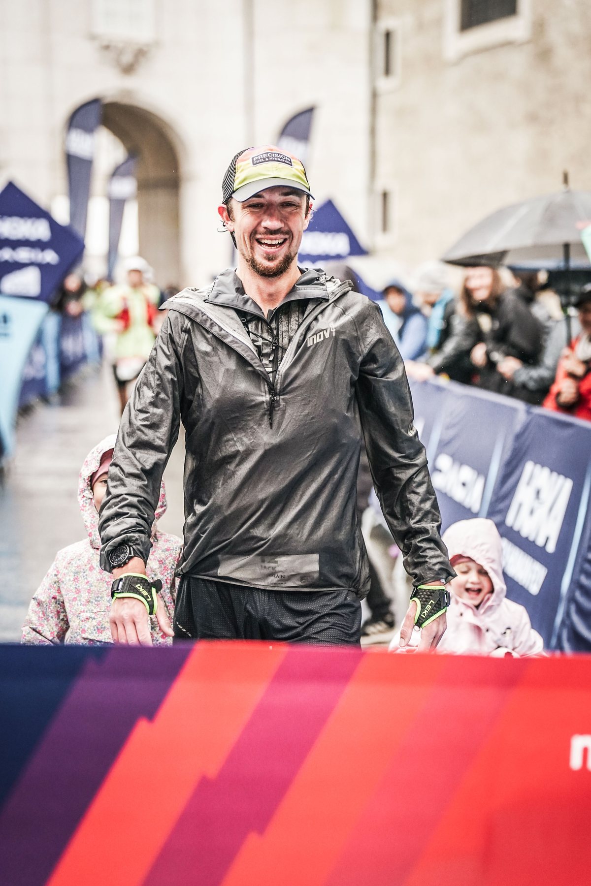 Jack Chamberlain in a soaked jacket, smiling at the Mozart 100 finish line in Salzburg.